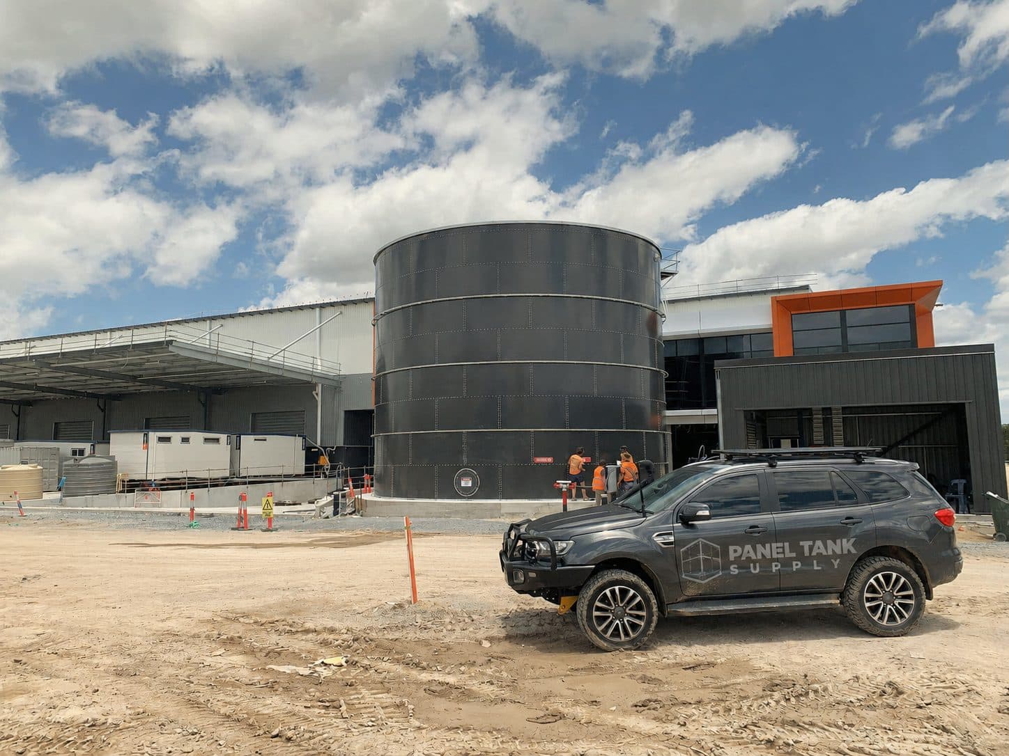 Large glass fused to steel storage tank beside a Panel Tank Supply vehicle at an industrial project site